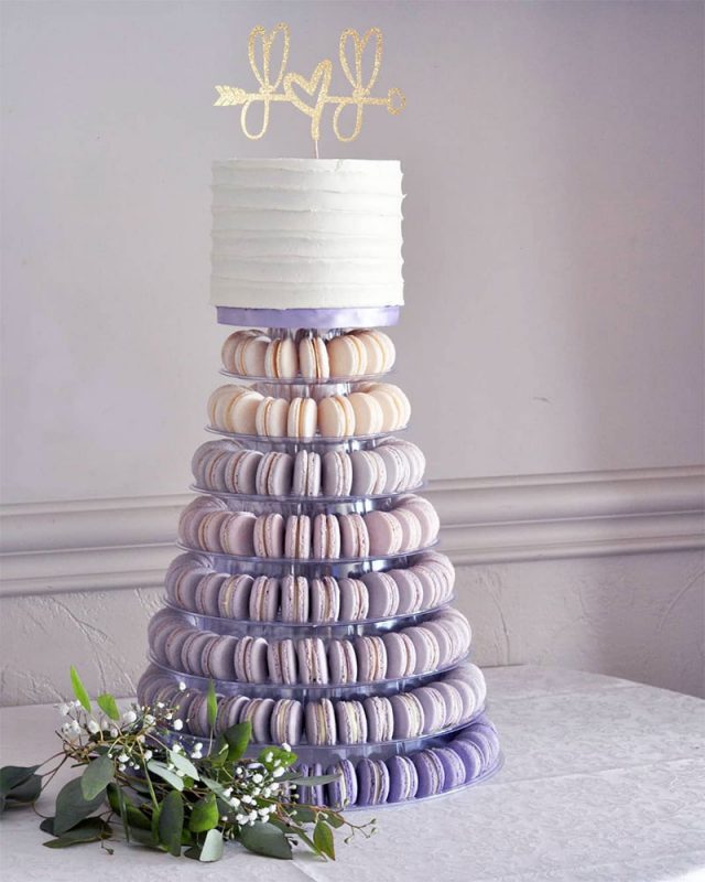 Pastel de boda con fondant y macarrones en tonos lilas y morados.