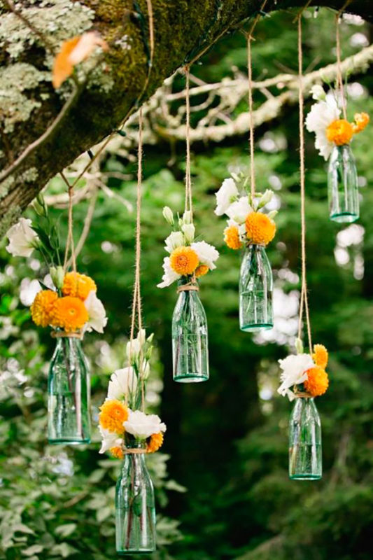 botellas de vidrio acompañadas de ramos de flores 